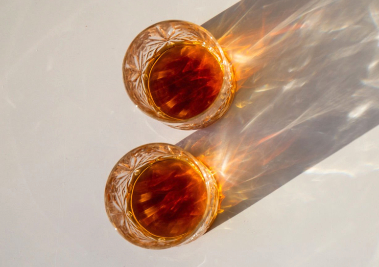 Two alcoholic drinks rest in the sunshine